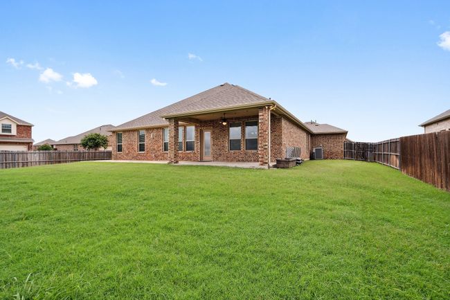 Rear view of property with a fenced backyard, brick siding, a patio area, and roof with shingles | Image 5