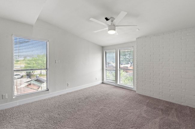 Carpeted empty room with ceiling fan, vaulted ceiling, baseboards, and brick wall | Image 32