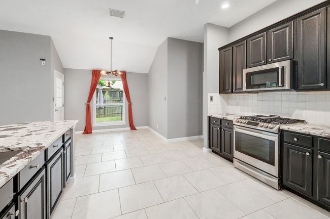 Kitchen with tasteful backsplash, visible vents, baseboards, stainless steel appliances, and light stone counters | Image 13