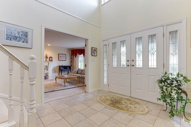 Foyer entrance with light tile patterned floors, baseboards, a towering ceiling, stairway, and ornamental molding | Image 22