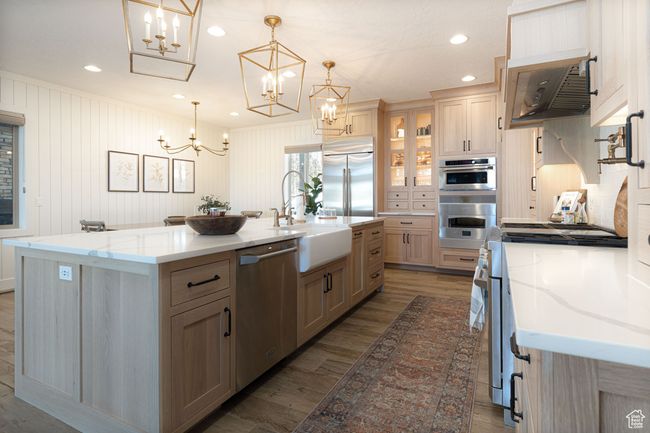 Kitchen with a kitchen island with sink, wood finished floors, stainless steel appliances, a sink, and an inviting chandelier | Image 4