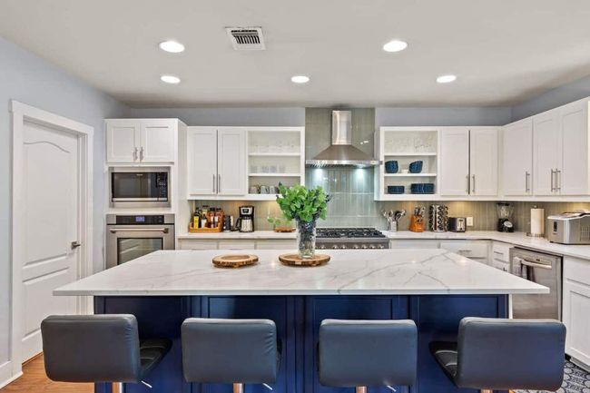 Kitchen with wall chimney range hood and a breakfast bar area | Image 10