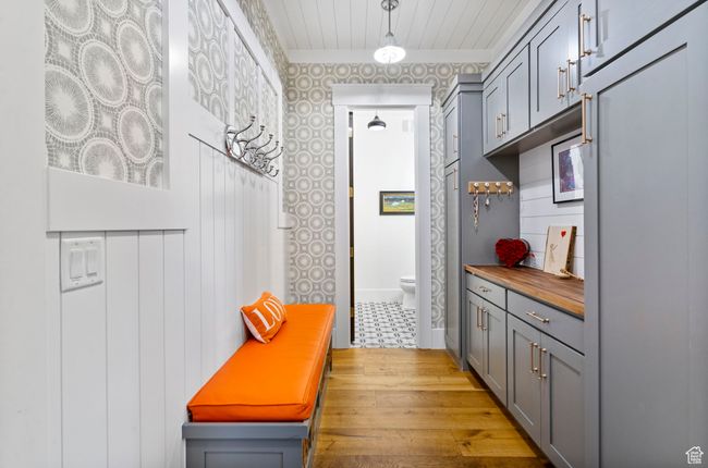 Mudroom with wood finished floors, baseboards, wallpapered walls, and wooden ceiling | Image 33