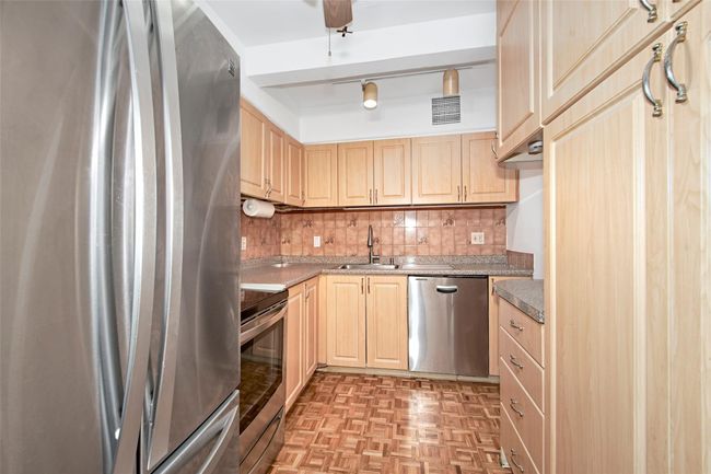 Kitchen with stainless steel appliances, light brown cabinetry, decorative backsplash, and ceiling fan | Image 16