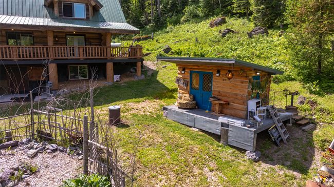 View of green lawn featuring an outdoor structure, a wooden deck, and a view of trees | Image 42