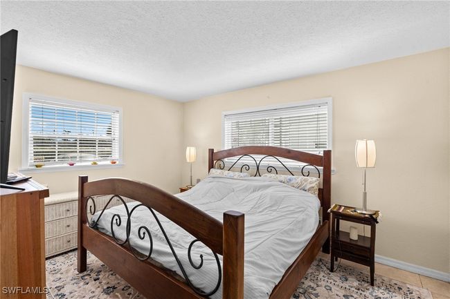 Bedroom featuring light tile patterned flooring, baseboards, multiple windows, and a textured ceiling | Image 16