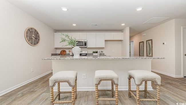 Kitchen featuring light stone counters, stainless steel appliances, an island with sink, and white cabinets | Image 8
