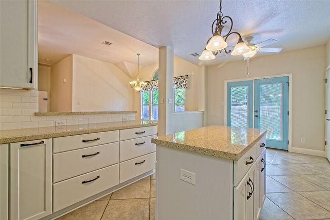 Kitchen with a chandelier, plenty of natural light, light tile patterned flooring, and a textured ceiling | Image 15