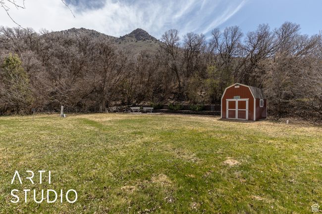 View of yard with a shed, a view of trees, a mountain view, and an outbuilding | Image 43