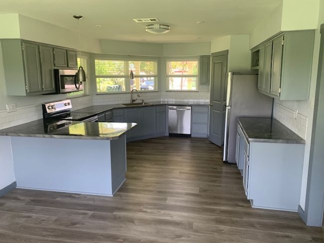 Kitchen featuring a peninsula, backsplash, stainless steel appliances, dark wood-style floors, and dark countertops | Image 13