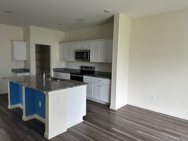 Kitchen with appliances with stainless steel finishes, dark wood finished floors, and white cabinetry | Image 21