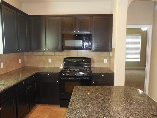 Kitchen with black appliances, dark stone countertops, and decorative backsplash | Image 7