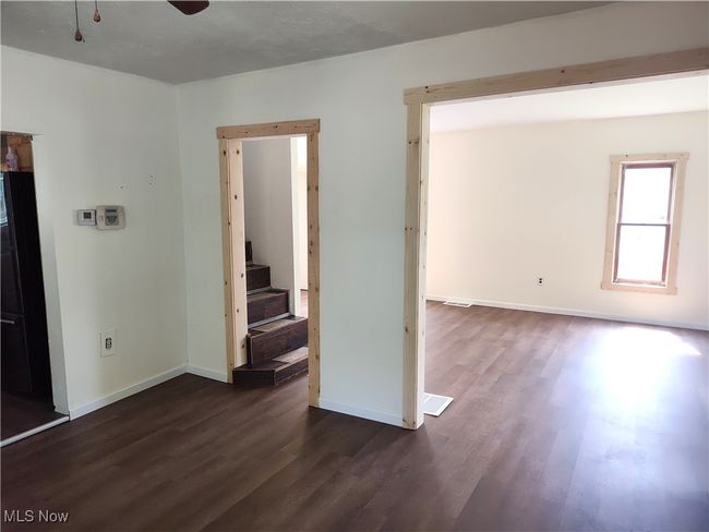 Unfurnished room featuring dark wood-style flooring, baseboards, a ceiling fan, and stairway | Image 10