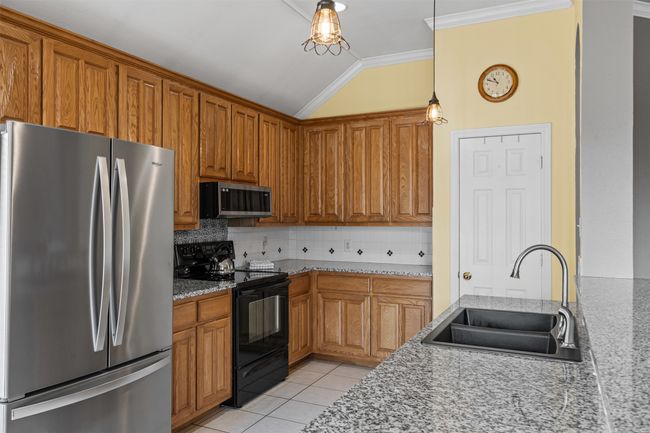Kitchen with stainless steel appliances, a sink, lofted ceiling, crown molding, and tasteful backsplash | Image 10