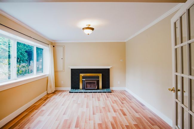 Unfurnished living room featuring baseboards, crown molding, wood finished floors, and a fireplace | Image 20