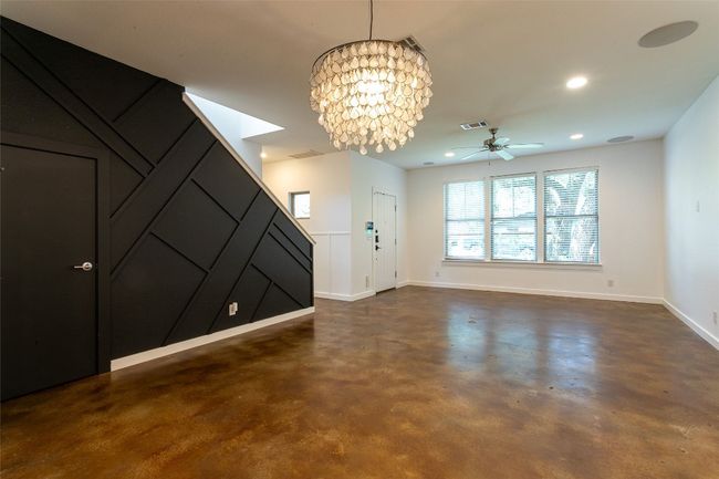 Unfurnished living room featuring concrete floors, a chandelier, a ceiling fan, and recessed lighting | Image 8