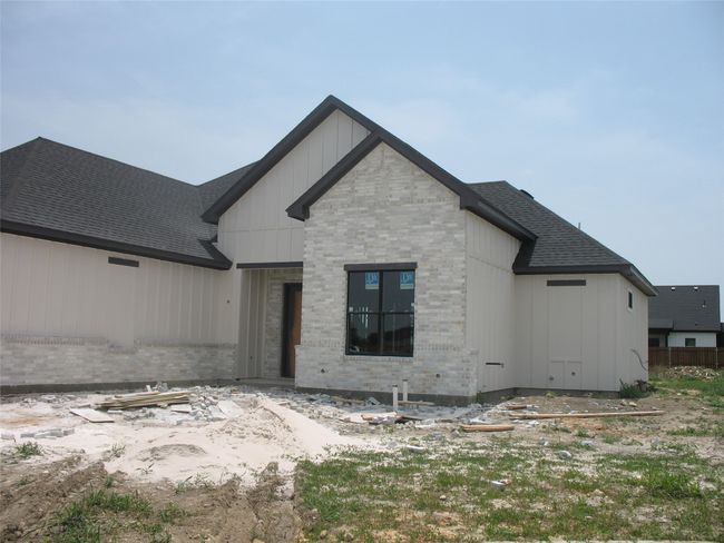 View of front of home with brick siding, roof with shingles, and board and batten siding | Image 5