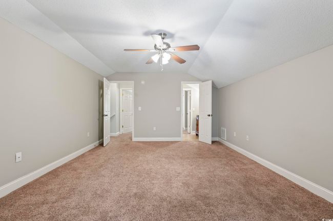 Unfurnished bedroom featuring lofted ceiling, light colored carpet, baseboards, and a ceiling fan | Image 27