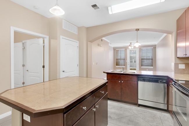 Kitchen with stainless steel appliances, a sink, a center island, and decorative light fixtures. All new paint. | Image 6