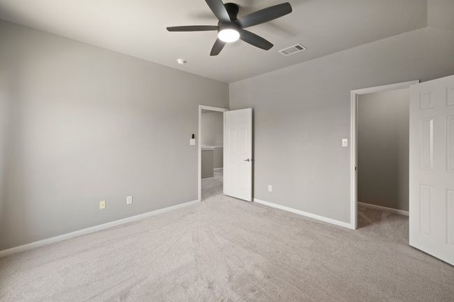 Unfurnished bedroom featuring carpet, baseboards, a walk in closet, and ceiling fan | Image 25