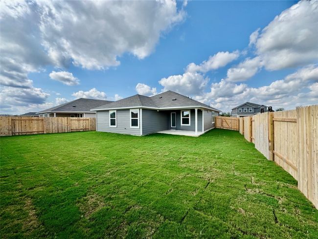 Rear view of house with a patio area, a fenced backyard, and a shingled roof | Image 5