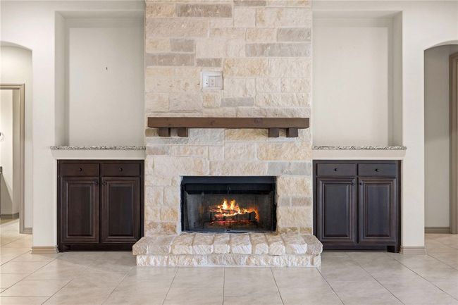 Room details with baseboards, arched walkways, and a stone fireplace | Image 9