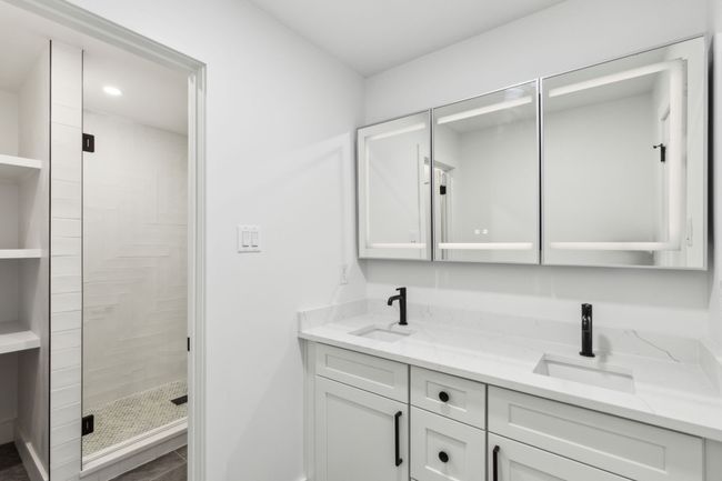 Secondary bathroom has dual sinks and custom LED mirrors with inset medicine cabinet. | Image 23