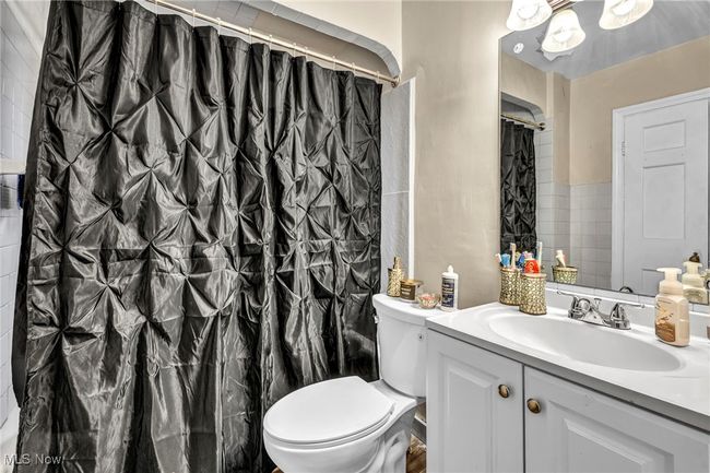 Bathroom featuring a shower with shower curtain, toilet, and vanity | Image 12