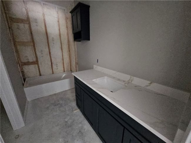 Full bathroom featuring vanity, a tub, and unfinished concrete flooring | Image 8