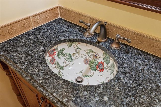 GORGEOUS CUSTOM SINK IN POWDER ROOM IS SURROUNDED BY GRANITE AND STUNNING DECORATIVE TILE BORDER | Image 21