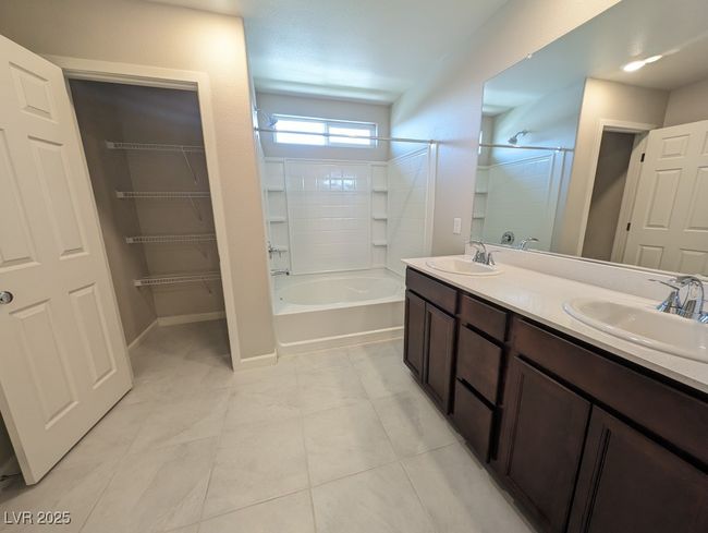 Full bathroom with double vanity, shower / bathtub combination, tile patterned flooring, and a closet | Image 24