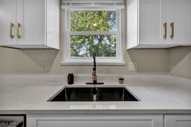 Kitchen view of white cabinets and light stone counters | Image 10