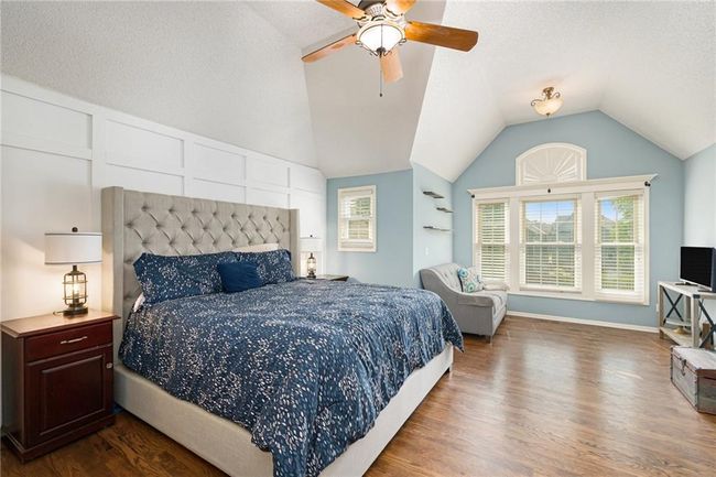 Bedroom with wood finished floors, lofted ceiling, a textured ceiling, and a ceiling fan | Image 28