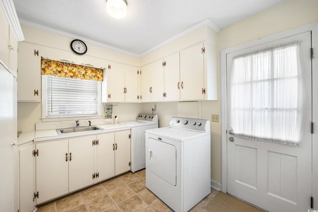 Laundry room with washer and dryer, cabinet space, healthy amount of natural light, crown molding, and light tile patterned floors | Image 13