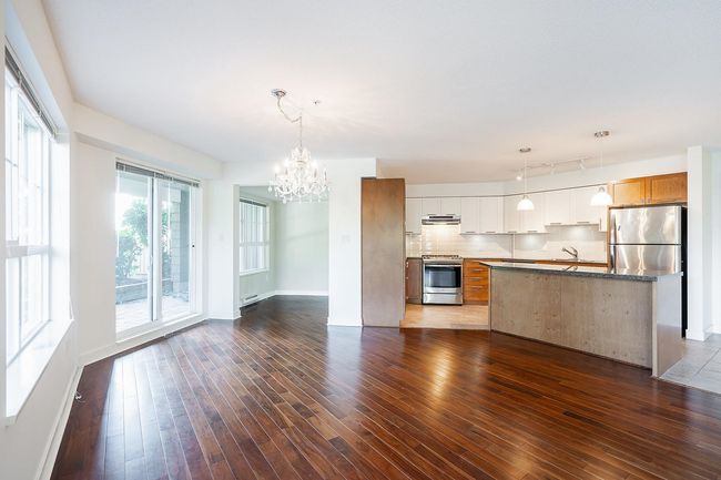 Kitchen with a notable chandelier, dark wood-style flooring, stainless steel appliances, and under cabinet range hood | Image 10