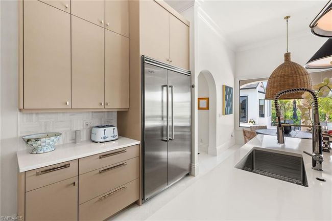 Kitchen with light countertops, ornamental molding, decorative light fixtures, stainless steel built in fridge, and backsplash | Image 14