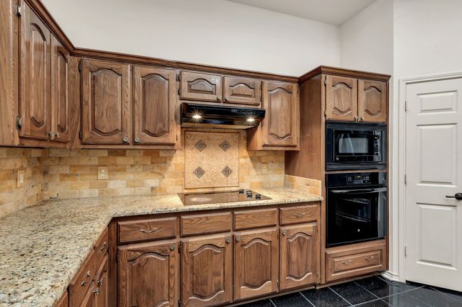 Kitchen featuring black appliances, decorative backsplash, under cabinet range hood, granite counters | Image 13