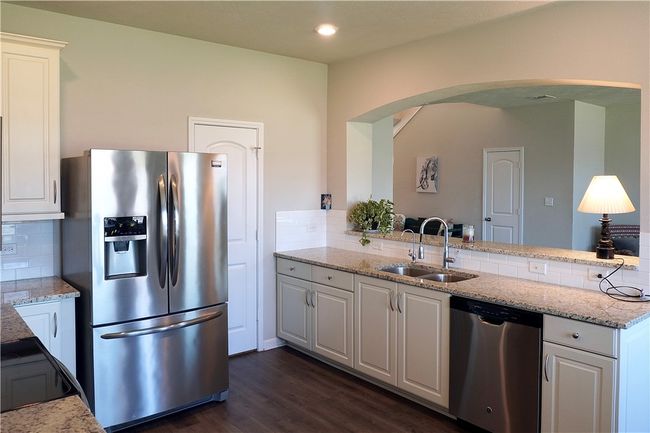 Kitchen featuring stainless steel appliances, a sink, arched walkways, tasteful backsplash, and white cabinetry | Image 5