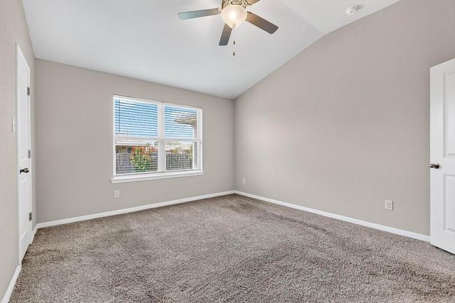 Carpeted empty room featuring vaulted ceiling, a smoke detector, and a ceiling fan | Image 19