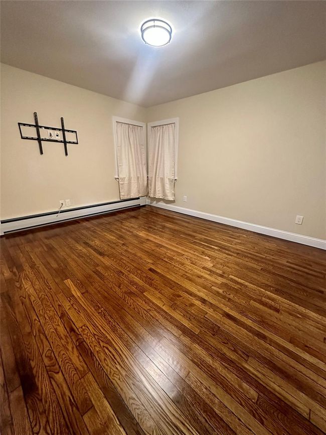 Spare room featuring dark wood-style floors, baseboard heating, and baseboards | Image 5