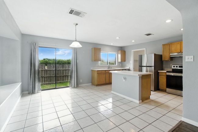 Kitchen with stainless steel appliances, under cabinet range hood, light countertops, a kitchen island, and recessed lighting. | Image 6