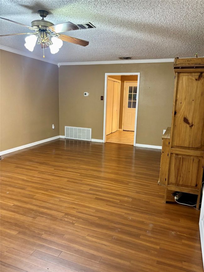 Unfurnished room featuring crown molding, wood finished floors, a ceiling fan, and a textured ceiling | Image 6