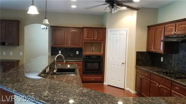 Kitchen featuring arched walkways, black appliances, decorative backsplash, dark stone countertops, and recessed lighting | Image 27