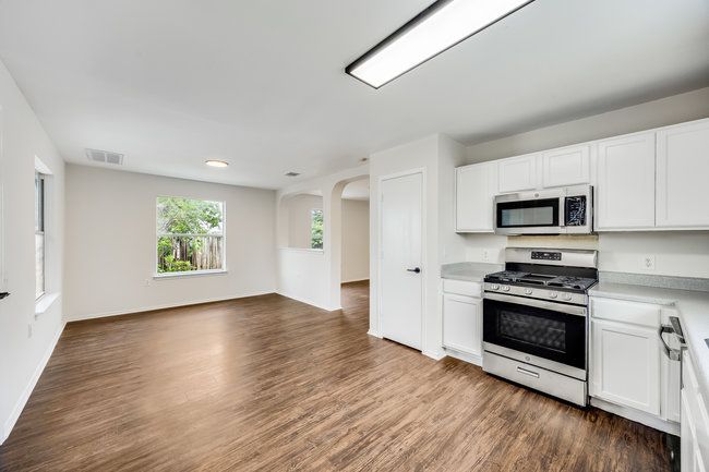 Kitchen with appliances with stainless steel finishes, open floor plan, dark wood finished floors, and white cabinetry | Image 13