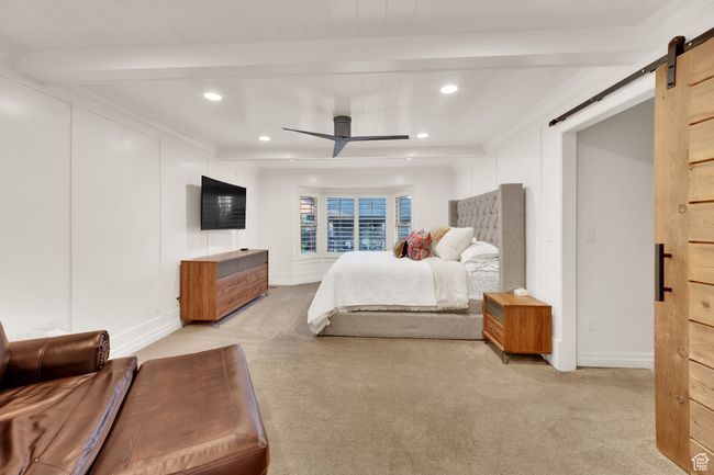 Bedroom with a barn door, beam ceiling, light colored carpet, recessed lighting, and baseboards | Image 16