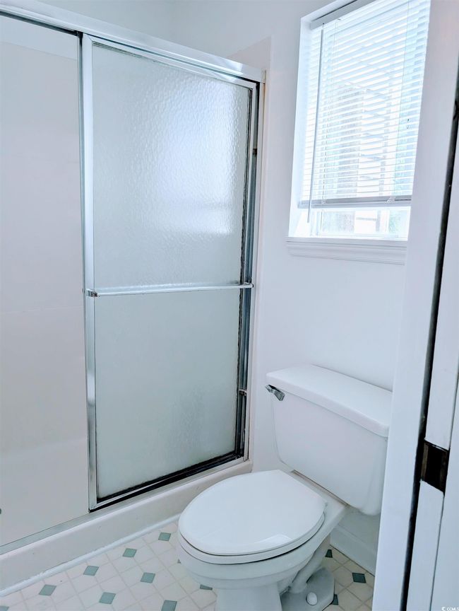 Full bathroom featuring a shower with door and toilet | Image 13