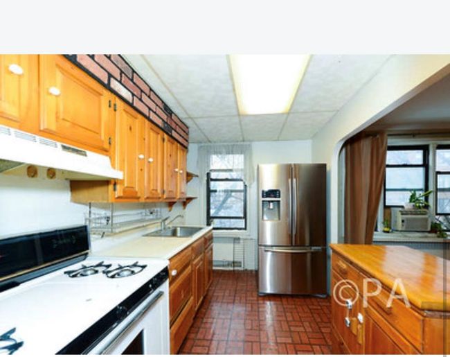 Kitchen with under cabinet range hood, stainless steel fridge with ice dispenser, light countertops, brick floor, and white range with gas cooktop | Image 5