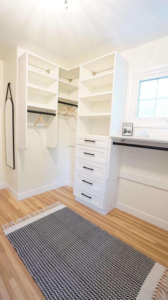 The walk-in closet is light and bright thanks to a ton of natural light, a new designer light fixture, and a neutral paint color. A full length mirror adds to the functionality and convenience of the space. | Image 19
