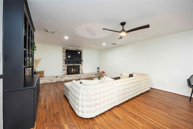 Spacious living room featuring accent walls around the fireplace and TV area, complemented by bright interiors and attractive flooring. | Image 6