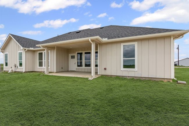 Rear view of house with a lawn, a patio, board and batten siding, and a shingled roof | Image 36